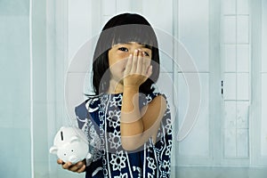 Asian little girl hand holding white piggy bank, learn to saving for the future concept