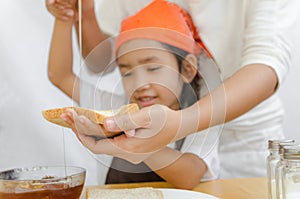 Asian little girl hold the bread and honey dipper stick with mot