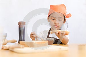 Asian little girl hold the bread and honey dipper stick on white