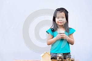 Asian little girl holding the lid of glass bottle with a coin  smiling proudly  looked at camera.