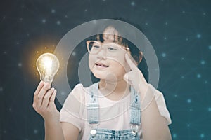 Asian Little girl holding light bulb in the black background, ideas with innovative technology and Electricity, education and peop