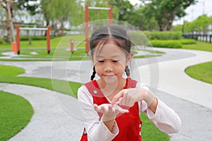 Asian little girl kid gesture finger touch something and looking without theme on hands while in the garden