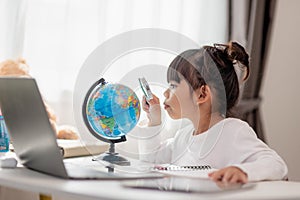 Asian little girl is learning the globe model, concept of save the world and learn through play activity for kid education at home