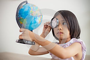 Asian little girl is learning the globe model, concept of save the world and learn through play activity for kid education at home