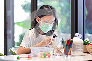 Asian little girl making DIY art and craft in workshop