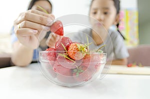 Asian little girl and mother picking straberry in glass bowl