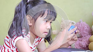 Asian little girl play video game in living room.