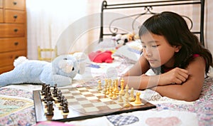 Asian little girl playing chess with teddy rabbit