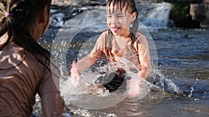 Asian little girl playing in the forest stream with her sister. Active recreation with children on river in summer.