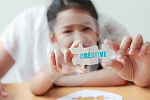 Asian little girl playing jigsaw puzzle with her mother for fami