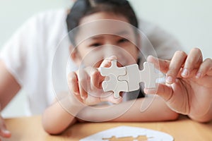 Asian little girl playing jigsaw puzzle with her mother for fami