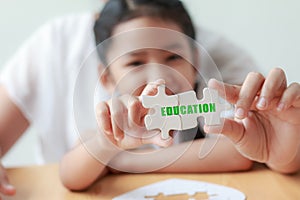 Asian little girl playing jigsaw puzzle with her mother for family concept shallow depth of field select focus on hands