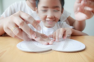 Asian little girl playing jigsaw puzzle with her mother for family concept shallow depth of field select focus on hands