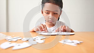 Asian little girl playing jigsaw puzzle select focus on hand shallow depth of field
