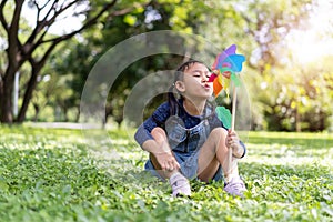Asian little girl playing with paper windmill in the garden