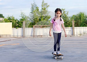 Asian little girl playing skateboard and smile with happiness againts blue sky select focus shallow depth of field