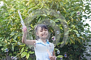 Asian little girl playing soap bubbles in the garden.