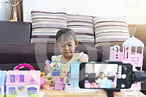 Asian little girl playing toys at home. With recording making video blogger