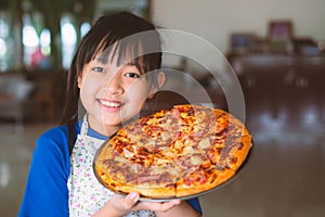 Asian little girl preparing homemade pizza with smile and happy