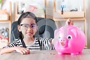 Asian little girl in putting coin in to piggy bank shallow depth of field select focus