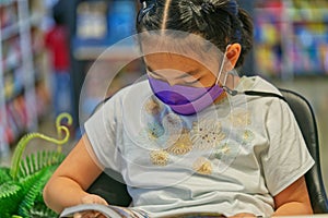 Asian little girl is reading a book