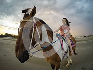 Asian little girl riding a horse on the beach in the evening,sunset with a girl on horseback,travel in Hua Hin,Prachuap Khiri Khan