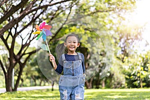 Asian little girl running in park playing with paper windmill