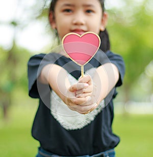Asian little girl showing wooden sign heart shallow depth of fie