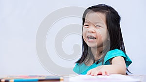 Asian little girl sits at the back of a study table wood. Children are laughing and having fun in art class.