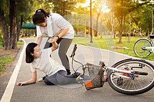 Asian little girl sitting down on the road with a leg pain due to a bicycle accident, the bike fall near the female child,cute