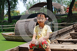 Asian little girl sitting on a wood boat