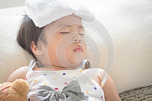 Asian little girl sleep and sick on sofa with cooler gel on her