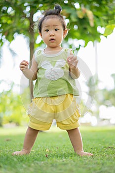 Asian little girl is standing on the lawn at the park, .Little girl learn to stand, baby girl with a birthmark, birthmark on his