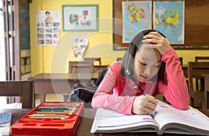 Asian little girl student using the idea,thinking and meditation to do homework in classroom,portrait of child student studying