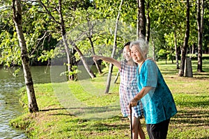 Asian little girl supporting,watching something senior woman with walking stick,happy smiling grandmother,granddaughter in outdoor