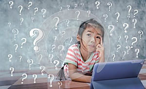 Asian little girl thinking with a question mark symbol in gray background. Kid ideas and brainstorm