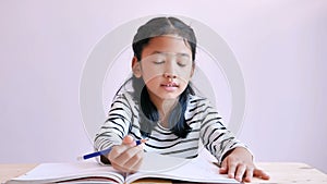 Asian little girl use a pencil drawing something on the notebook