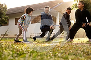 Asian little girl warming up in the early morning with multi generation family at countryside home yard, stretching bodies workout