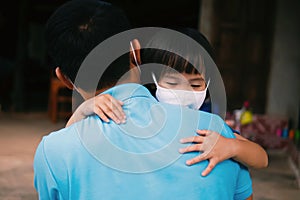 Asian little girl wearing protective face mask hugging her father on rural home background, family love and care lifestyles amid photo