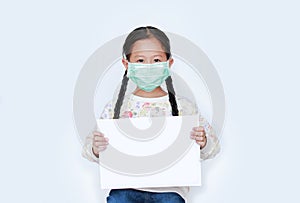 Asian little girl wearing protective mask with showing blank white paper on white background. Child holding empty white copy space