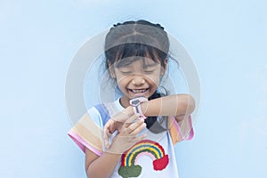 Asian little girl wearing a smart watch on her wrist and is calling cheerfully.