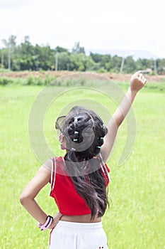 Asian little girl wearing sunglasses and cloth mask, stood with arms akimbo, clenched hands and arms up while traveling on holiday