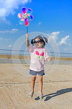 Asian little girl with wind turbine toy in hands