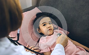 Asian little girl a woman slept in a pillow on the sofa for a female doctor using stethoscope on a heartbeat at home