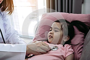 Asian little girl a woman slept in a pillow on the sofa for a female doctor using stethoscope on a heartbeat at home