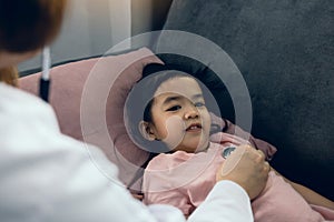 Asian little girl a woman slept in a pillow on the sofa for a female doctor using stethoscope on a heartbeat at home