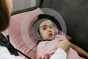 Asian little girl a woman slept in a pillow on the sofa for a female doctor using stethoscope on a heartbeat at home