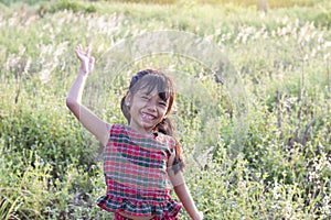 Asian little girl wore a dress made of Thai loincloth or Kamar band or Commer band standing and laugh bright in the fields.