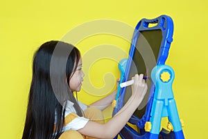 Asian little girl writing on empty blackboard. Student and development concept