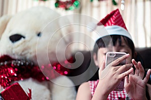 Asian little girl in a xmas Santa Claus hat using a smart phone